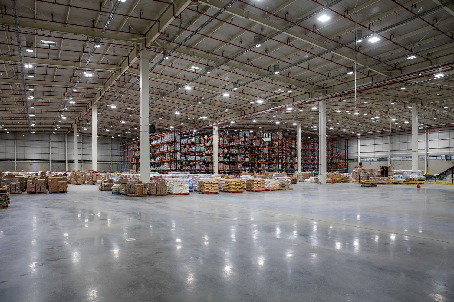 Vista aérea de un gran complejo logístico industrial con múltiples muelles de carga, destacando las cubiertas y áreas exteriores que requieren sistemas de iluminación de alta eficiencia.