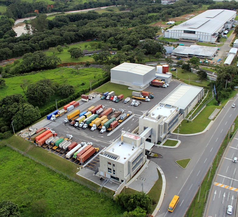 Vista aérea de una infraestructura industrial protegida por sistemas de seguridad Dinova en Colombia, incluyendo camiones, contenedores y edificios.